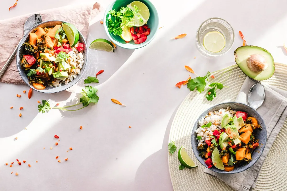 Two bowls of colorful plant-based salad with grains, chickpeas, avocado, and fresh vegetables, seen from above.